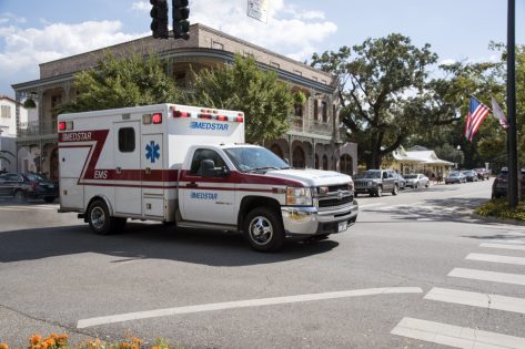 An ambulance on an emergency call driving through the town center of Fairhope.