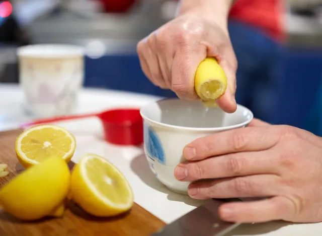 Man's hand squeezing half a lemon into a bowl