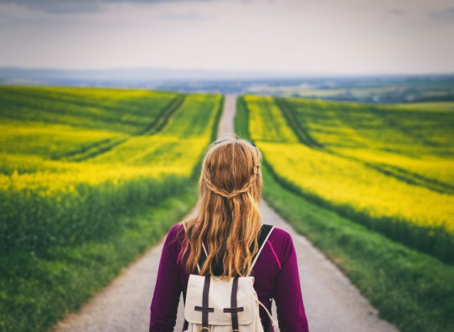 Long way to go. Woman travelling in countryside. Tourist standing on the road. Travel concept. Challenge of journey