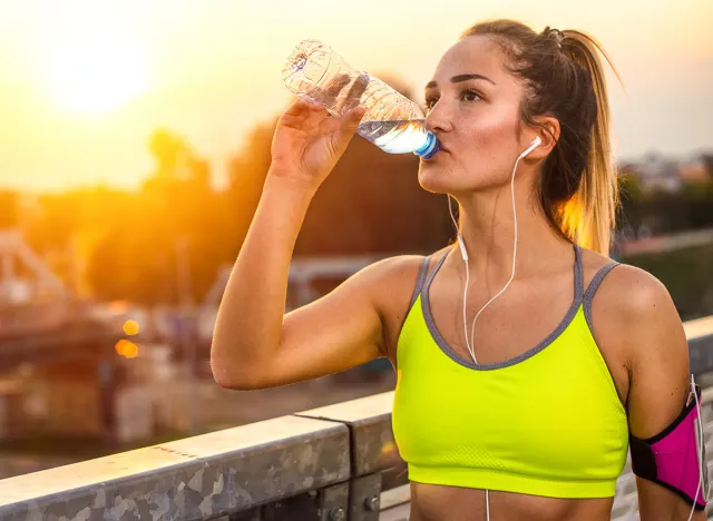 Young woman jogger resting drinking water