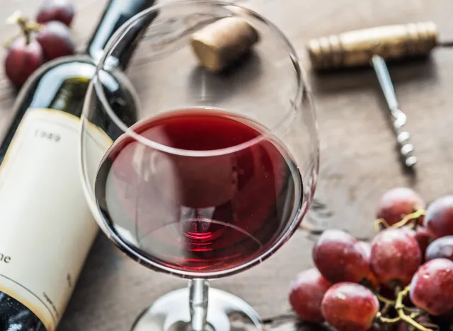 Wine glass, wine bottle and grapes on wooden background. Wine tasting.