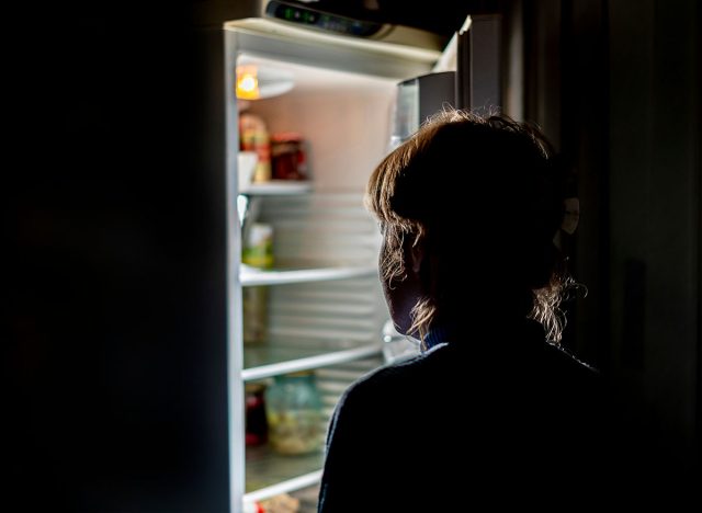 woman by the open refrigerator at night