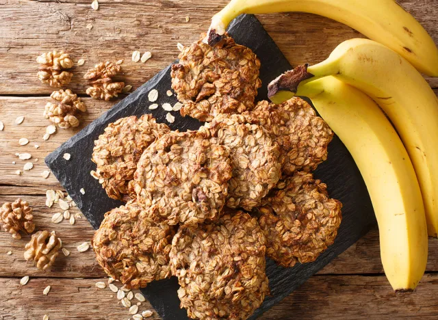 Homemade low-calorie banana cookies with oatmeal and walnuts close-up on a slate board on the table. Horizontal top view from above