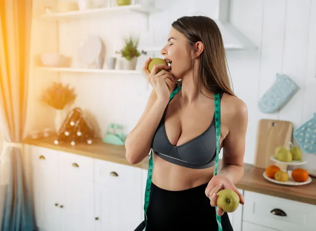 Sporty woman eating apple and preparing to make fresh juce. Healthy food lifestyle