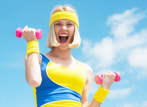 Attractive young fitness woman holding dumbell. Fitness woman. Fit woman in nature in spring. Happy blonde lifting dumbbells