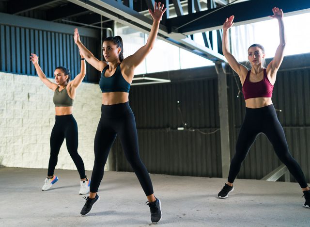 Active and healthy women doing jumping jacks during a HIIT class. Three beautiful and fit women working out at the gym with power training