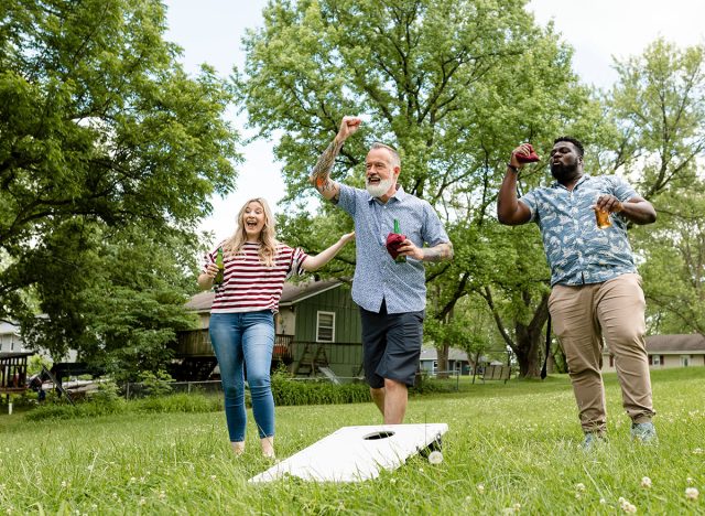 Friends playing cornhole at a summer party in the park