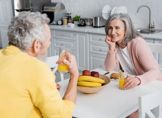 Happy woman looking at blurred husband near breakfast at home