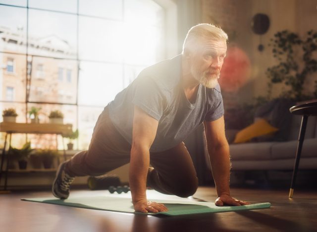 Strong Athletic Fit Middle Aged Man Doing Mountain Climber Exercises During Morning Workout at Home in Sunny Apartment. Healthy Lifestyle, Fitness, Recreation, Wellbeing and Retirement.