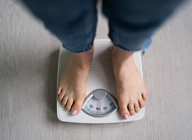 Scale Woman Feet Standing On Weight Scale In Bathroom. Cholesterol Control