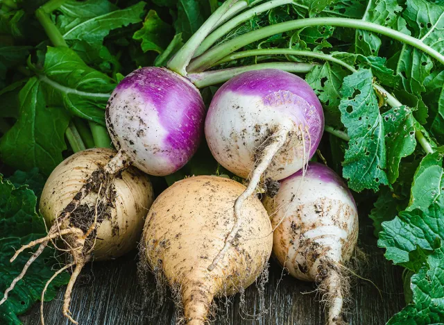 Bunch of purple and yellow turnips on a rustic wooden table.