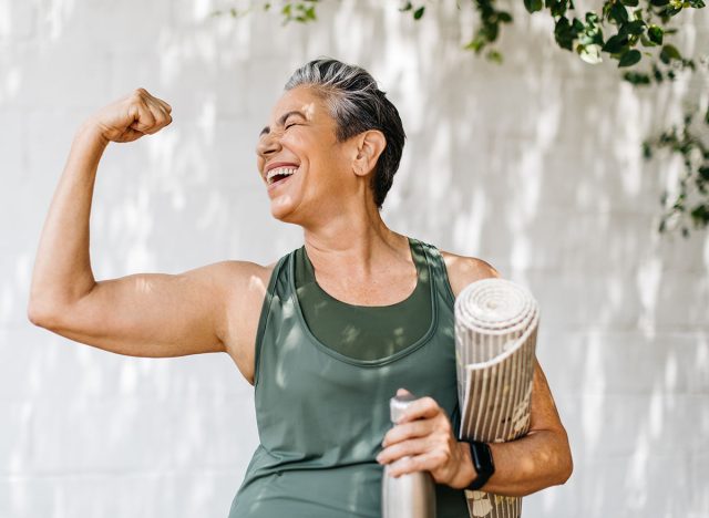 Happy elderly woman celebrating her fitness achievement after a great outdoor workout session, flaunting her strong bicep. Fit senior woman expressing her pride in her successful exercise routine.