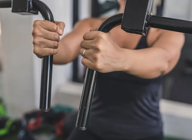 An anonymous married asian woman does a set of chest flys on a pec deck machine at the gym. Targeting the pectoralis muscles