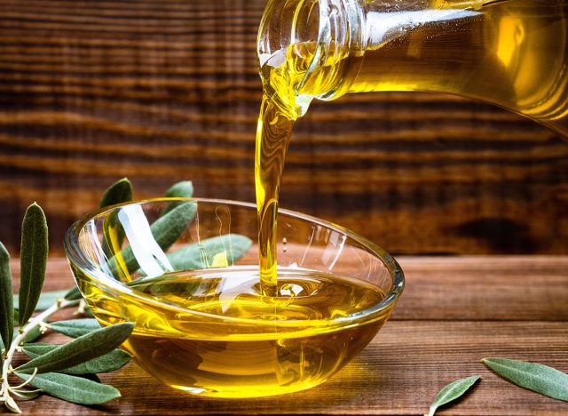 Organic olive oil pouring from carafe into glass bowl