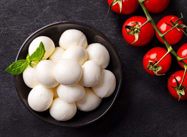 Mozzarella cheese balls with tomatoes and basil. Dark slate background. Top view.