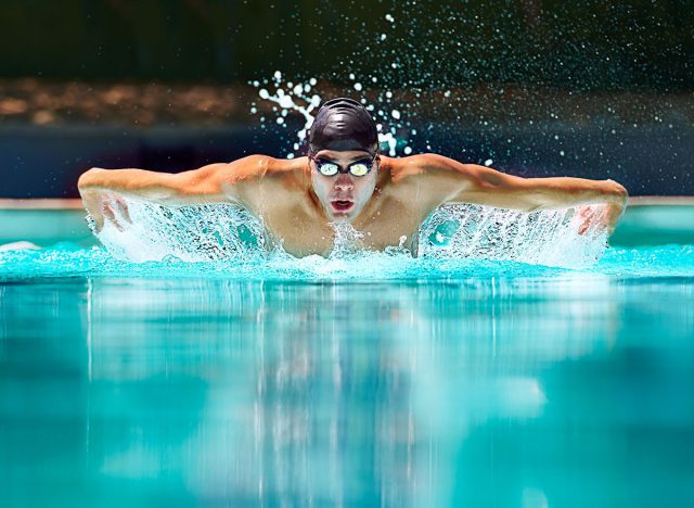 Fitness, sport and training with man in swimming pool for competition, workout and energy. Strong, water splash and cardio with male swimmer and practice for athlete, championship and race at gala