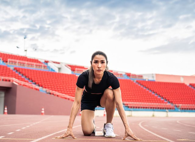 Asian young sportswoman sprint on a running track outdoors on stadium. Attractive strong athlete girl runner exercise and practicing workout speed running marathon on the race for olympics competition