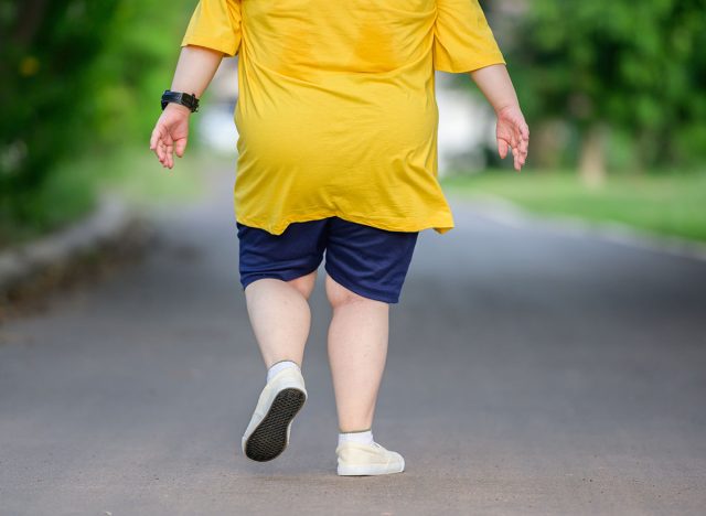 back view fat asian girl exercising By walking to burn fat and jogging slowly, fat woman walks for exercise in a natural park.