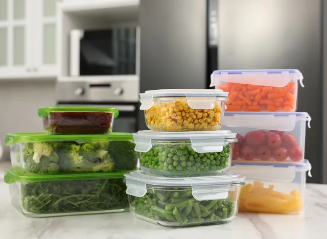 Glass and plastic containers with different fresh products on white marble table in kitchen. Food storage