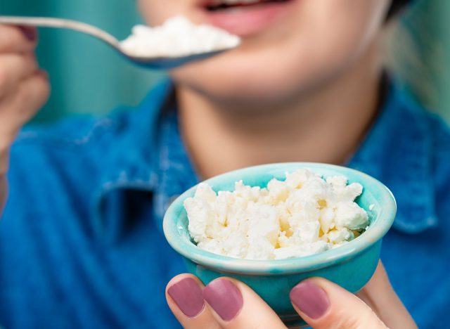 Close-up of a bowl of cottage cheese in the hands of a Caucasian woman. Focus on a bowl of cottage cheese.