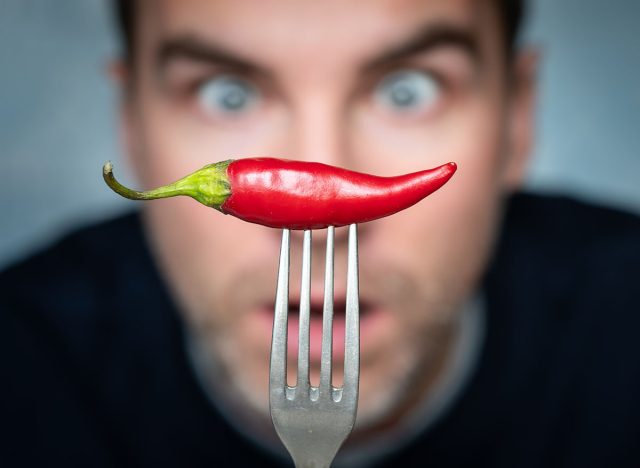 ridiculous expression of man with hot chillies in his hand. a man is afraid to eat hot peppers.