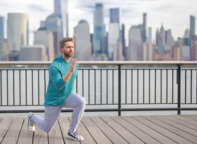 Man in fitness wear exercising near Manhattan. Healthy exercises. Active senior man is fitness exercising outdoor. Exercising after retirement. Senior man training legs muscles doing lunges exercise.