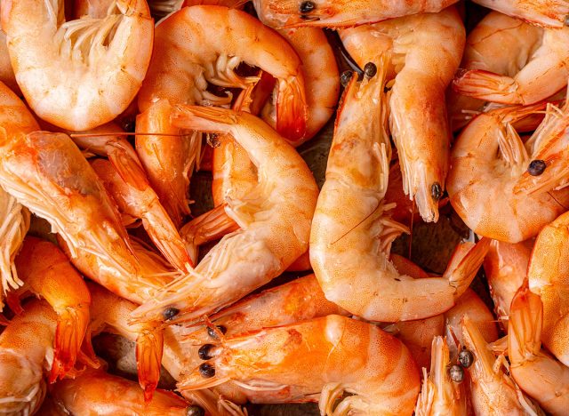 Frozen, boiled shrimp. Texture King prawns background. Seafood on the counter. Fish market. Close-up shot of seafood. Photo of shrimp in a supermarket. Wholesale of seafood. High quality photo