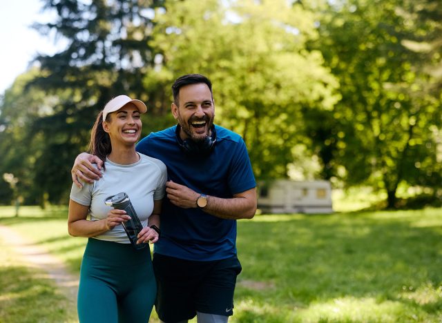 Happy couple of athlete laughing and having fun while working out in the park. Copy space.