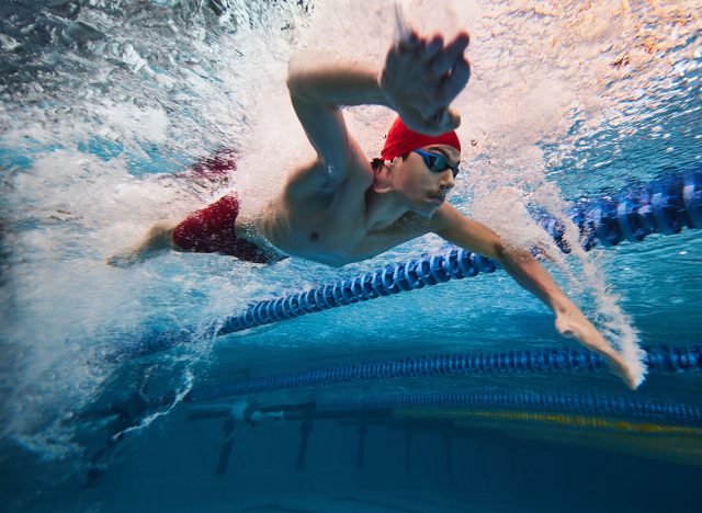 Water bubbles demonstrating speed. Young man, swimming athlete in motion in pool training, preparing for competition. Concept of professional sport, health, endurance, strength, active lifestyle