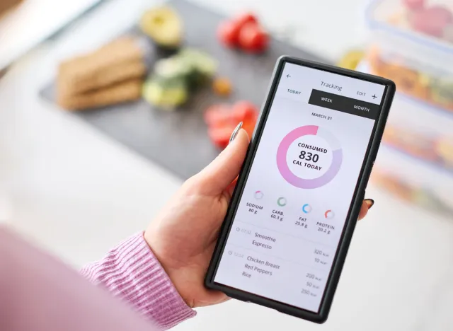 Close Up Of Woman Looking At Calorie Counting App On Mobile Phone At Home