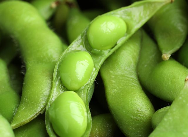 Fresh edamame pods with soybeans as background, closeup