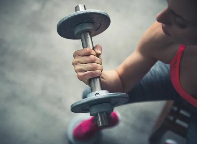 Body and mind workout in loft fitness studio. Closeup on fitness woman workout with dumbbell in urban loft gym