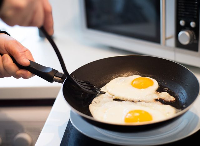 Unrecognizable man preparing fried eggs for breakfast. Close up.