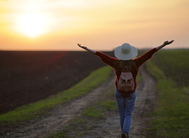 Inspired woman in nature with hands up, sunset, beautiful sky, natural background