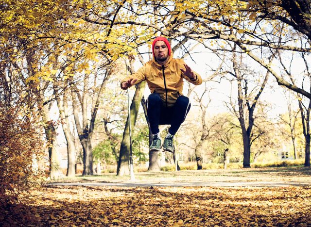 Jumping squats in park. Yang man exercise.