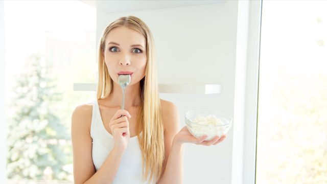 Photo portrait of excited cheerful beautiful pretty pleased cute attractive nice lady tasting cheese from plate in hands looking at camera.