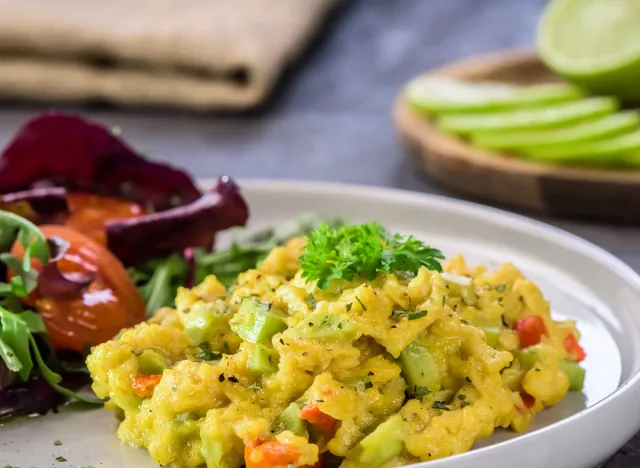 Scrambled eggs with pepper, avocado and parsley with salad made witch eco spinach and rucola - close up.