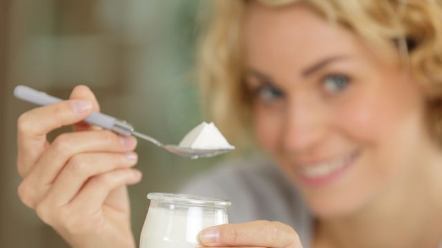 portrait of beautiful young woman eating yogurt at home