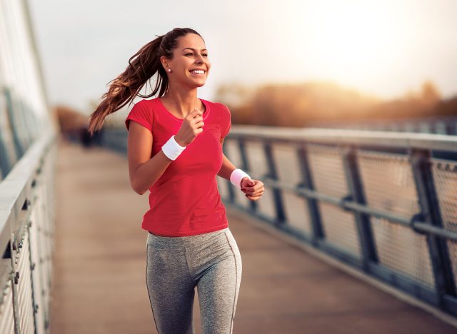 Beautiful fit woman in good shape jogging alone on city bridge.