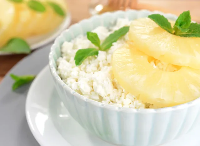 Bowl of tasty cottage cheese with pineapple on wooden table