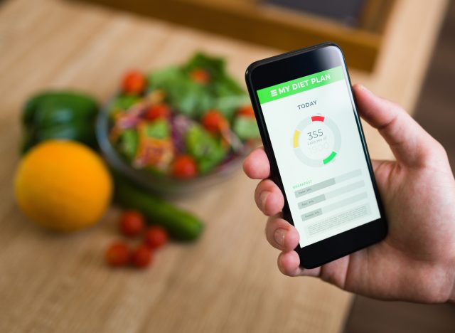 Healthy diet. Male hands holding a smartphone and keeping track of the calories of his food with a fitness app