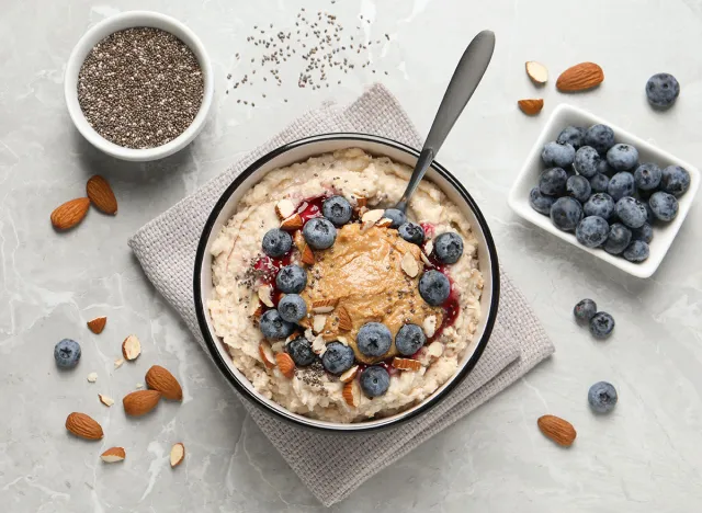 Tasty oatmeal porridge with toppings served on light grey table, flat lay