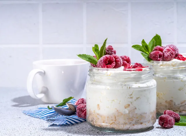 Overnight cheesecake oatmeal. Cheesecake morning breakfast layered parfafait dessert with homemade cottage cheese, mascarpone, oats and fresh raspberries, on sunny white concrete background copy space