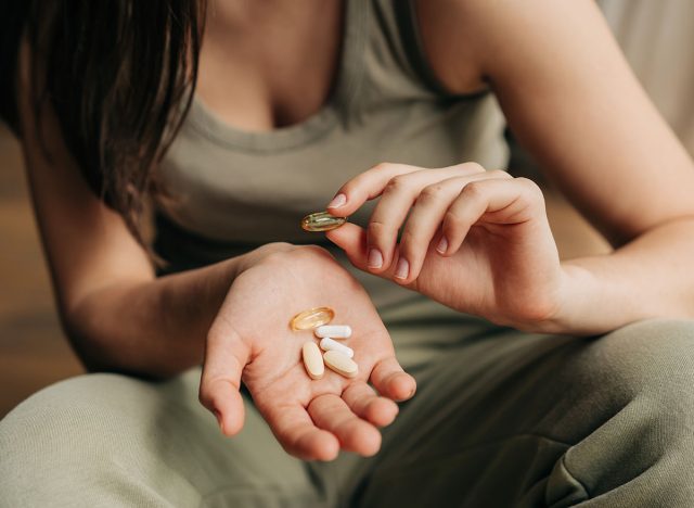 Closeup unrecognizable caucasian woman holding omega-3 fish oil capsules in hands and vitamins