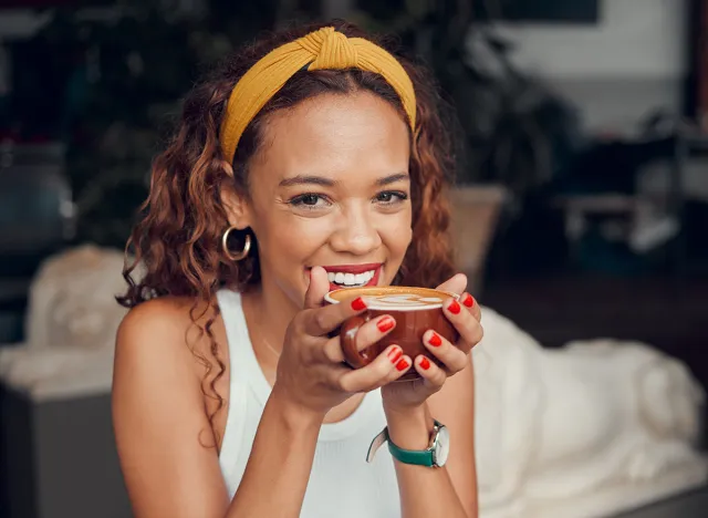 Smile, happy and coffee shop young woman enjoying a cup of tea in a restaurant or cafe on her lunch break. Portrait of happy customer drinking her morning caffeine or cappuccino with happiness