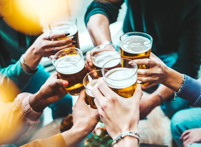 Group of people drinking beer at brewery pub restaurant - Happy friends enjoying happy hour sitting at bar table - Closeup image of brew glasses - Food and beverage lifestyle concept