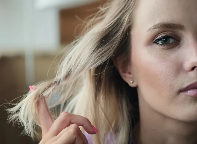 Cute attractive blonde twirls her hair on her finger. Close-up of a woman's face