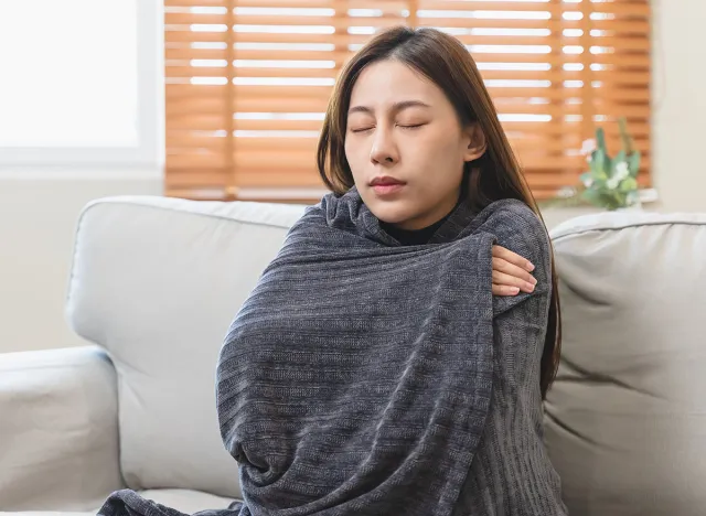 Young woman covering her body by blanket have shivering from cold weather in winter season