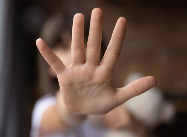 Stop. Blurred shot of little girl stretch hand show no sign mean prepare enough domestic violence bullying abuse violation of children rights. Close up focus on child palm making prohibition gesture