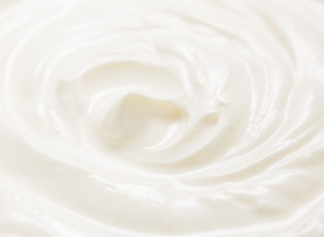 Sour cream or greek yogurt swirl texture, White cream background, close up. Dairy product. Delicious organic creamy yogurt. Milk cream